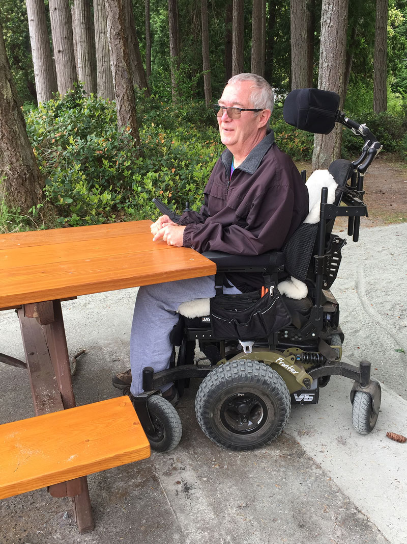 Man in a wheelchair sitting at a picnic table adapted by GaLTT for accessibility