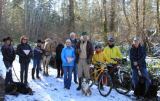 Group of people with share the trails "yield" signs. Group includes hikers, cyclists, a horse, and dogwalkers.