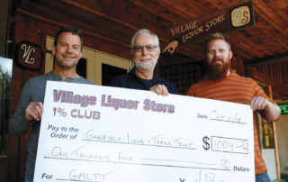 Three people holding up a giant cheque replica for $1004.