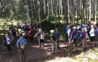 Large group of people on a trail listening to someone speak.
