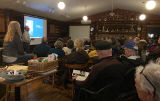 Speaker with a slide presentation standing in front of an audience.