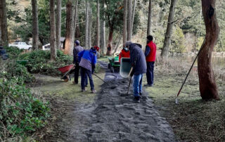Group of people spreading gravel mix on new accessible pathway