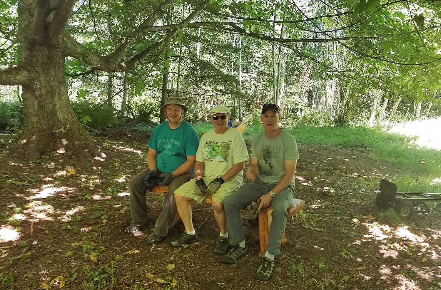 Three volunteers sitting on a newly installed resting bench