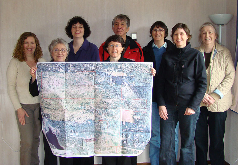 Group of people holding up a map showing the outlines of a new park.