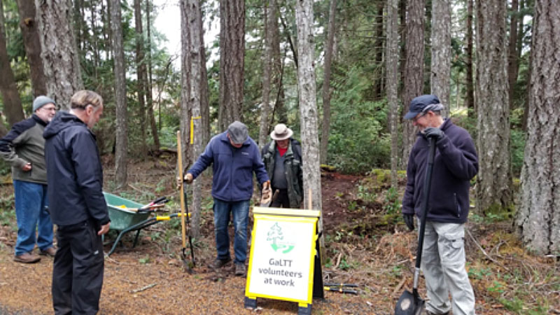 Group of people with tools by a "GaLTT volunteers at work" sign