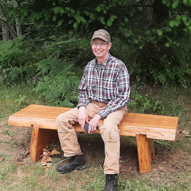photo of a man sitting on a beautiful bench handcrafted out of live-edge wood