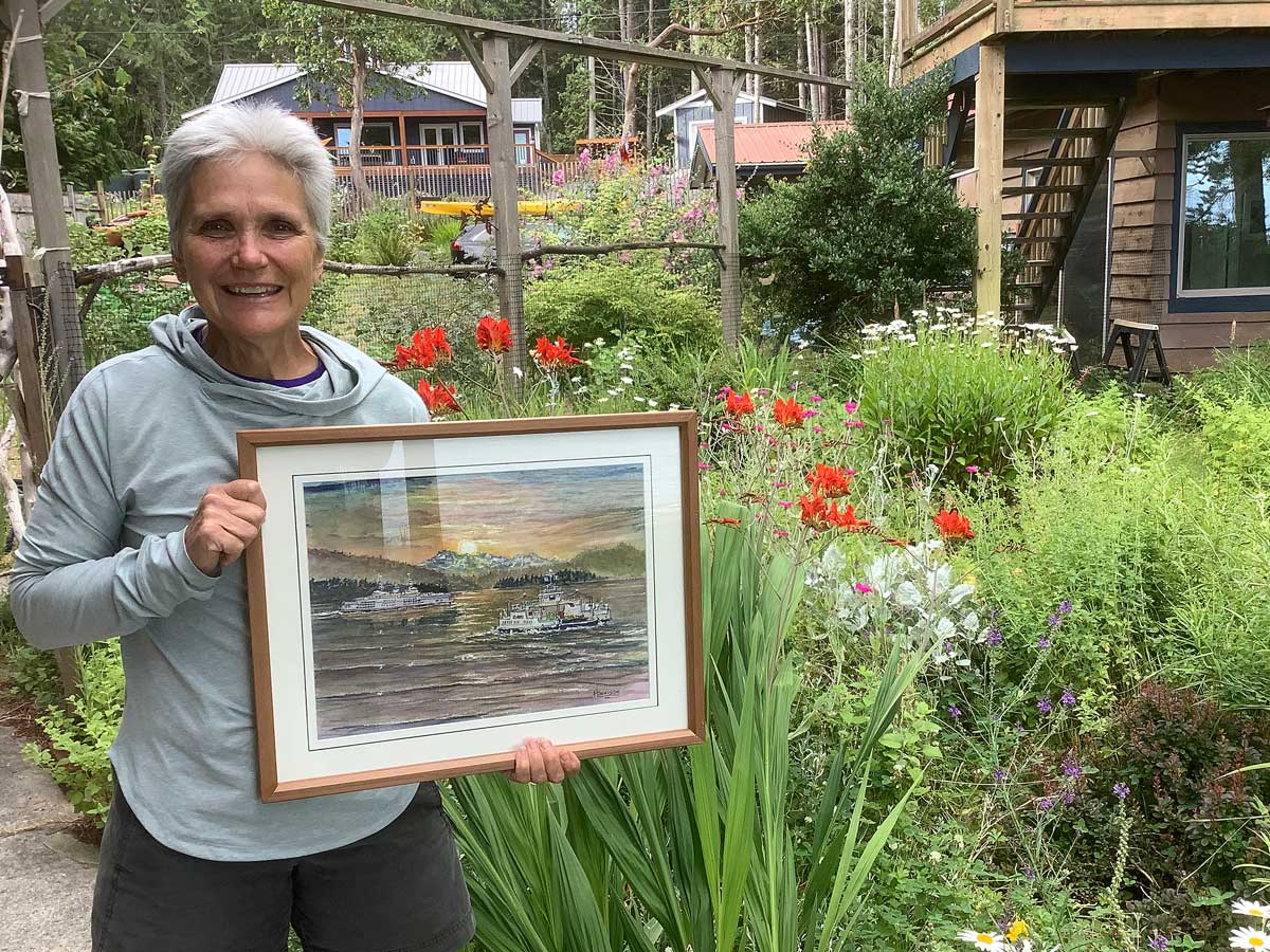 A woman stands in a garden holding a framed painting of ferries at sea.