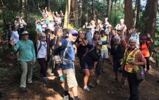 A large group of people on a trail, waving at the camera