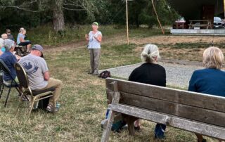 A group of people sit listening to a speaker wearing a GaLTT ballcap.
