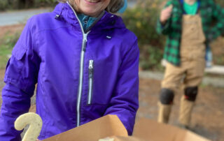 A smiling woman offers a box of cookies
