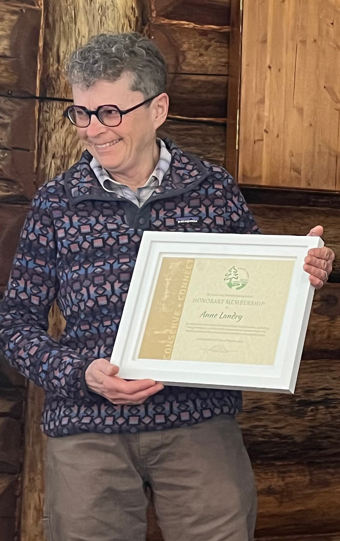A smiling woman holds a framed certificate.