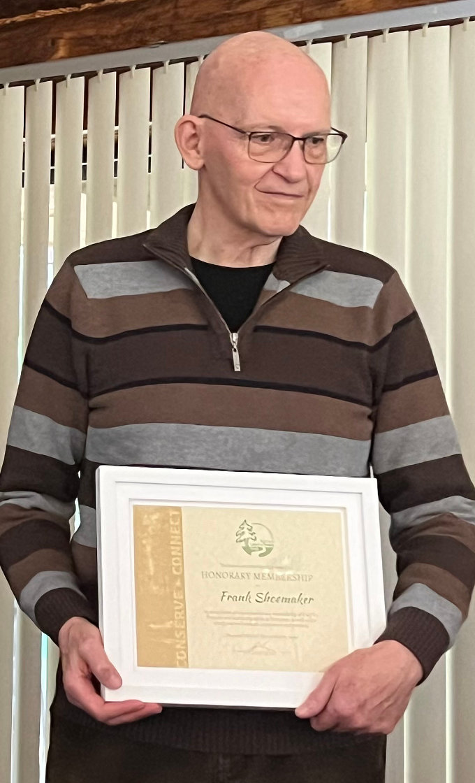 A smiling man holds a framed certificate.