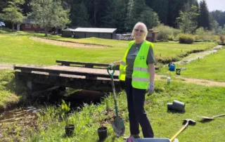 A proud volunteer with a shovel stands next to a riparian restoration area along the creek at the Gabriola Golf Course.