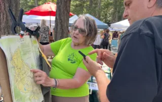 Volunteer Carol Chislett helping a visitor at the GaLTT table at the Gabriola Farmer's Market